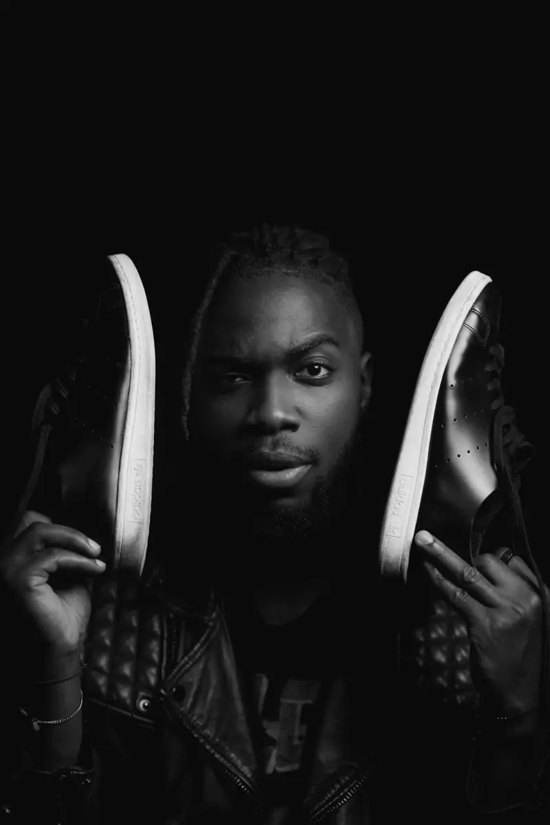 Studio-lit man holding sneakers